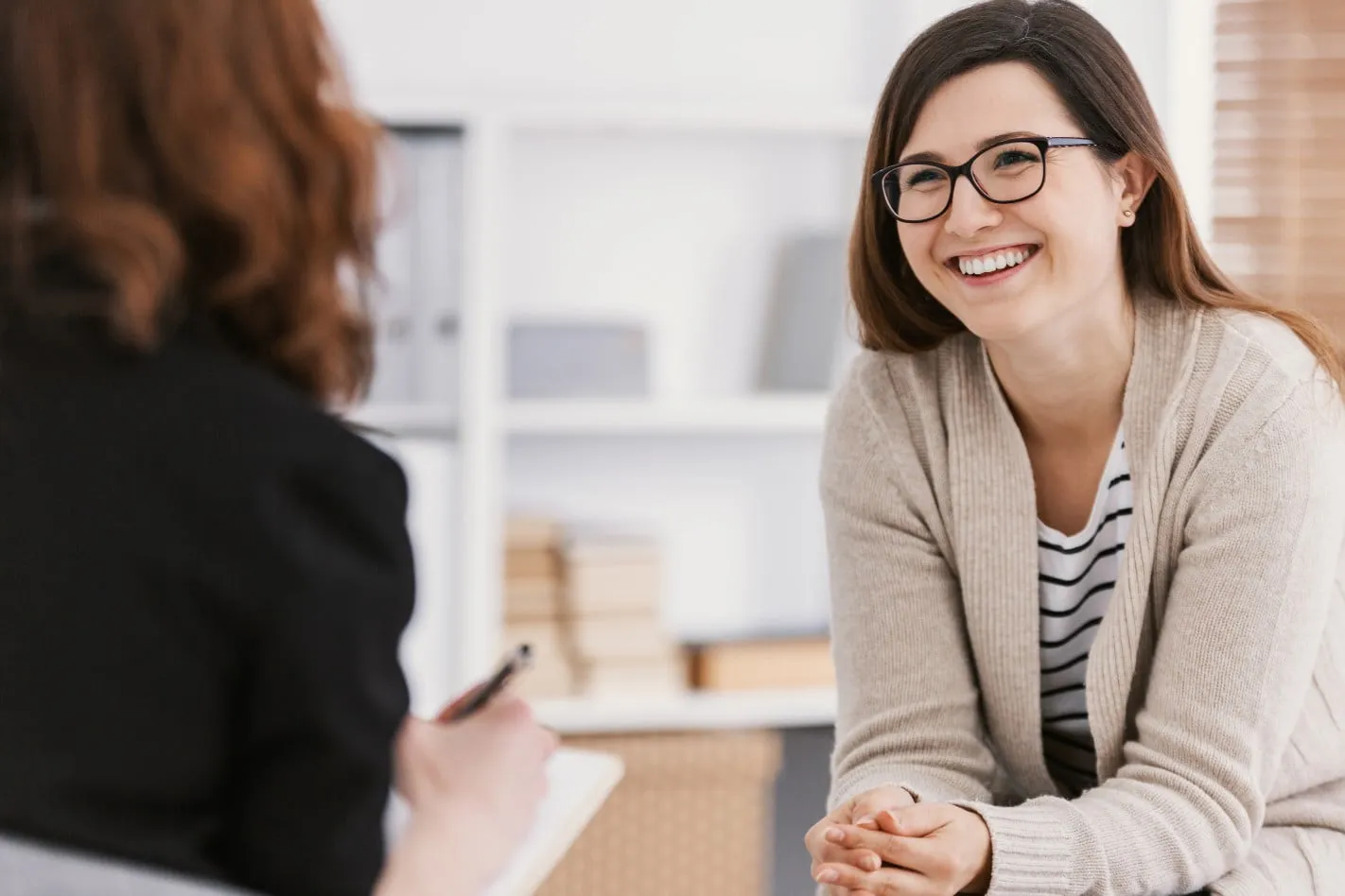 a women smiling and listening to someone in front of her.